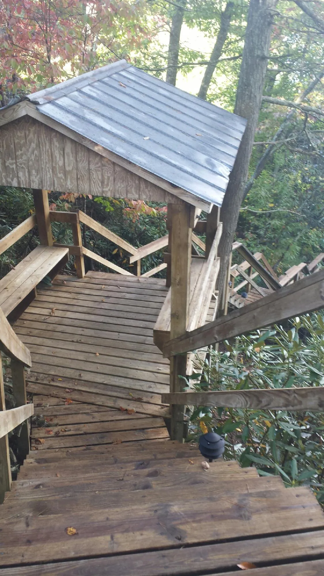 Metal roofed shelter over wooden steps on a wooded walkway — Skylight Repair & Installation work by our crew in Denver
